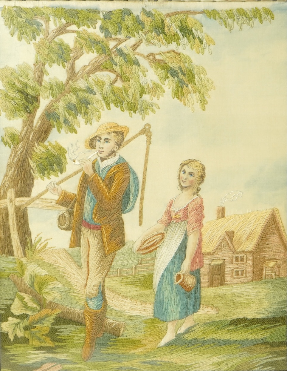 An early 20th silk embroidery of a boy and a girl in a country landscape by a tree and cottage. Worked in stem stitch with painted faces hands and background. Mounted with Verre Eglomise glass and a gilt rectangular fram